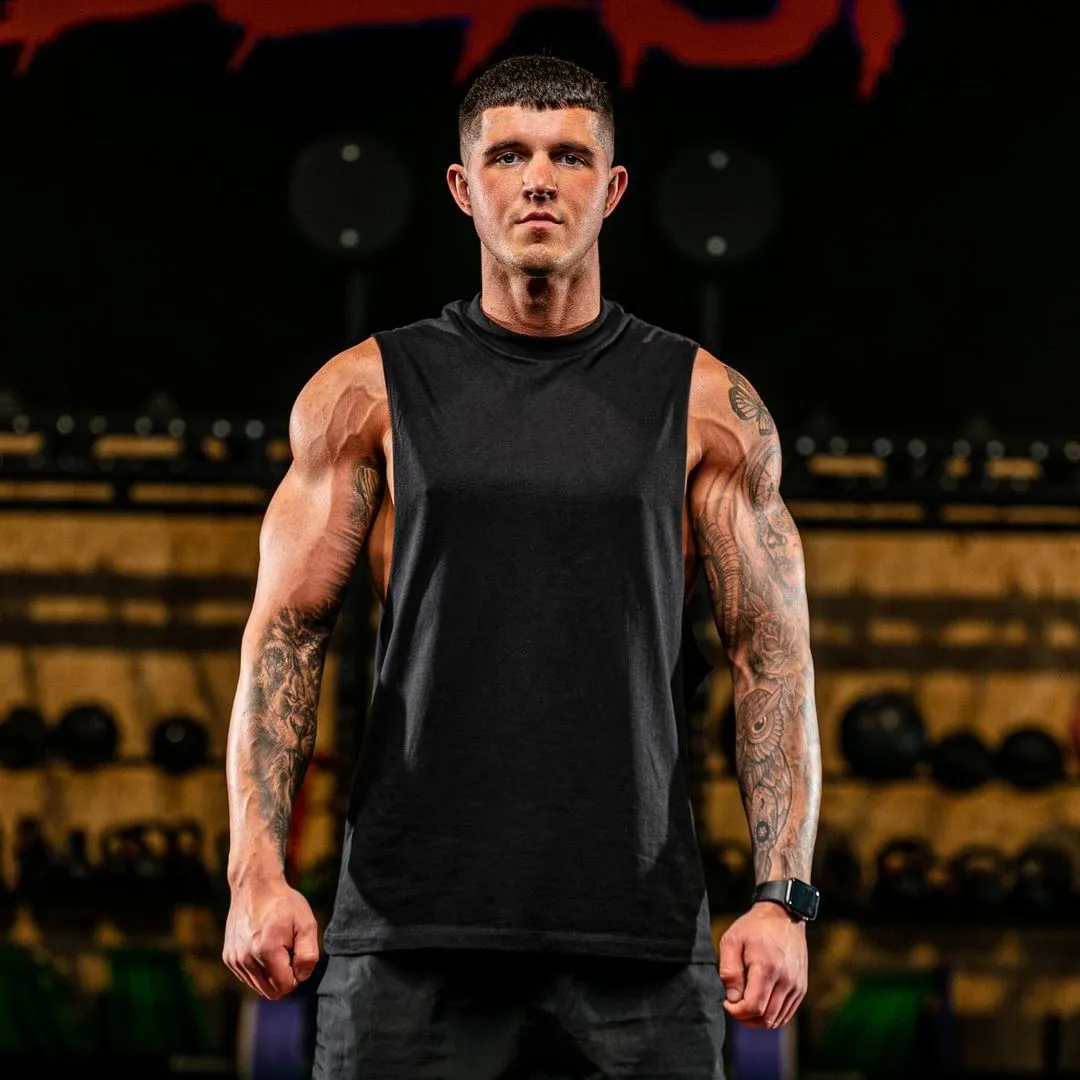 Portrait of Sam Foulkes, a personal trainer, confidently posing for a camera in a gym setting.